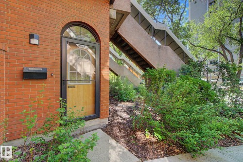 Red brick exterior featuring an arched entryway with a wood-paneled door - 11150 83 Avenue, Edmonton, AB 