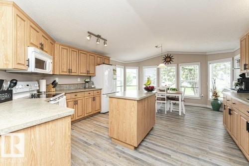 Open-concept kitchen featuring wood-finish cabinetry, a central island, and wood-finish flooring - 233 Oak Wood Drive, Edmonton, AB 