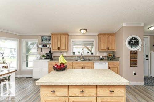Kitchen featuring a central island, wood-finish cabinetry, light-toned countertops, and a tile backsplash - 233 Oak Wood Drive, Edmonton, AB 