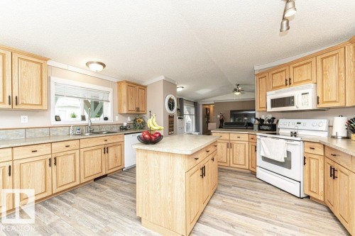 Kitchen featuring light wood-finish cabinetry, a central island, and light wood-finish flooring - 233 Oak Wood Drive, Edmonton, AB 