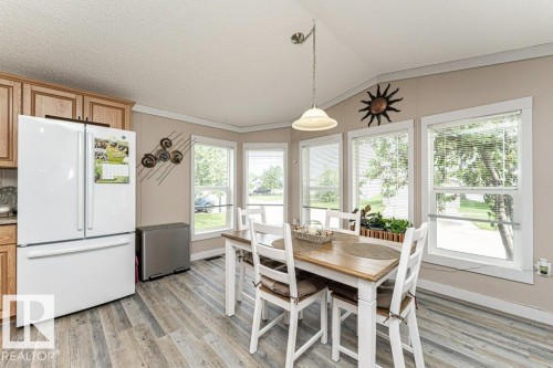 Dining area featuring a bay window with multiple panes, wood-finish flooring, and a pendant light fixture - 233 Oak Wood Drive, Edmonton, AB 