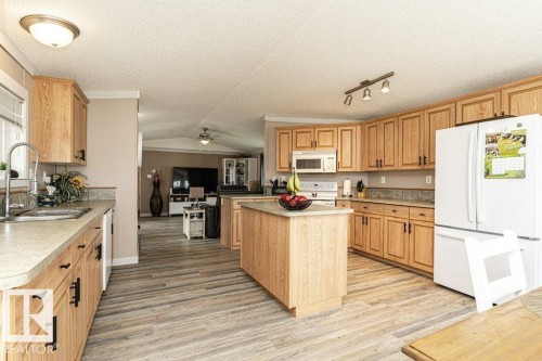 Spacious kitchen featuring light wood cabinetry, a central island, wood-finish flooring, ample countertop space, and integrated appliances - 233 Oak Wood Drive, Edmonton, AB 