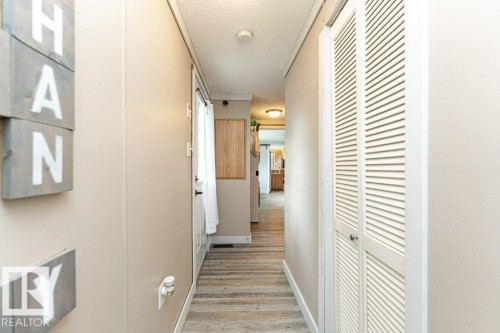 Hallway featuring wood-finish flooring, light-toned wall paneling, and a white louvered bifold door - 233 Oak Wood Drive, Edmonton, AB 