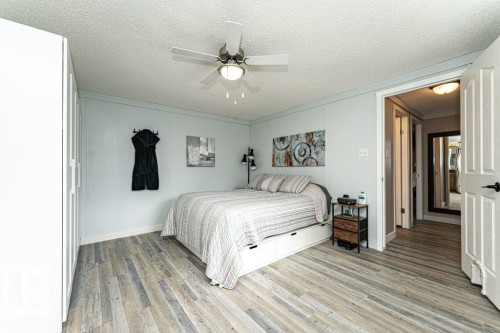 Room featuring wood-finish flooring, a ceiling fan with integrated lighting, paneled walls, and built-in white wardrobes - 233 Oak Wood Drive, Edmonton, AB 