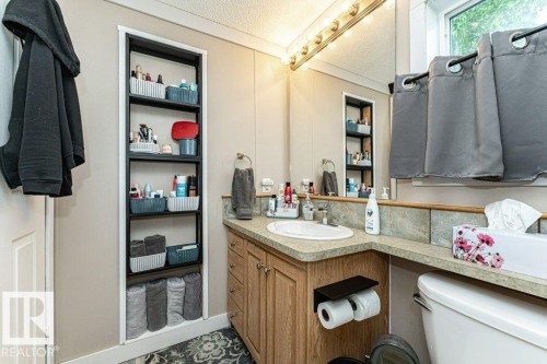Bathroom vanity featuring an integrated sink, wood-finish cabinetry, and a countertop with a tiled backsplash - 233 Oak Wood Drive, Edmonton, AB 