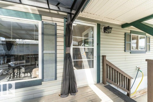 Covered porch entrance featuring a full-light storm door, horizontal siding, and decorative window shutters - 233 Oak Wood Drive, Edmonton, AB 