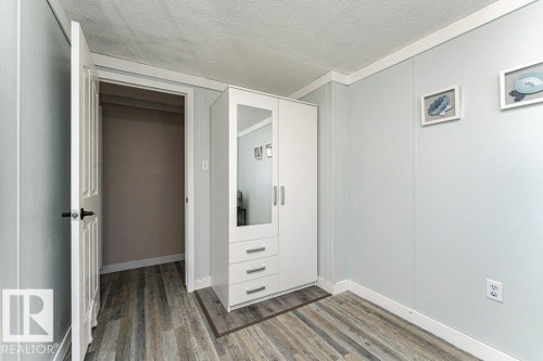 Room featuring light blue paneled walls and wood-finish flooring - 233 Oak Wood Drive, Edmonton, AB 