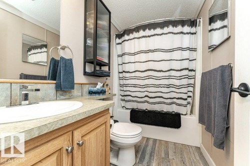 Bathroom featuring wood-finish flooring, a vanity with a laminate countertop, a tiled backsplash, and a shower-tub combination - 233 Oak Wood Drive, Edmonton, AB 