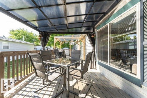Expansive outdoor deck featuring a translucent polycarbonate roof, wood railing, and vinyl siding - 233 Oak Wood Drive, Edmonton, AB 