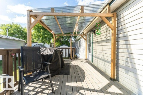 Exterior wood deck featuring a translucent roof covering, siding facade, a single entry door, and wood railings - 233 Oak Wood Drive, Edmonton, AB 