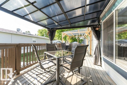 Expansive outdoor deck featuring wood flooring and a protective corrugated roof covering - 233 Oak Wood Drive, Edmonton, AB 
