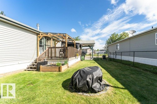 Expansive grass lawn featuring a raised planter box, a wood deck with railing, and a wood pergola - 233 Oak Wood Drive, Edmonton, AB 