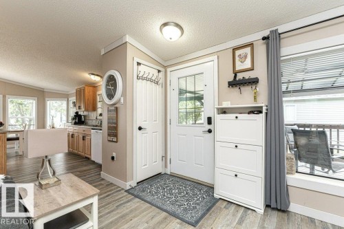 Entryway featuring a white door with glass inserts, wood-finish flooring, and a large window with blinds - 233 Oak Wood Drive, Edmonton, AB 