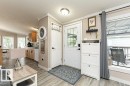 Entryway featuring a white door with glass inserts, wood-finish flooring, and a large window with blinds - 233 Oak Wood Drive, Edmonton, AB 