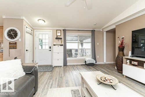 Living area featuring wood-finish flooring, neutral wall tones, a ceiling fan, and a transom window - 233 Oak Wood Drive, Edmonton, AB 