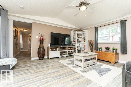 Open-concept living space with wood-finish flooring, vaulted ceilings, and a ceiling fan with integrated lighting - 233 Oak Wood Drive, Edmonton, AB 