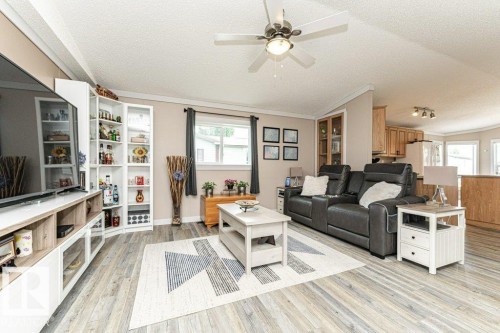 Expansive living area featuring wood-finish flooring, a ceiling fan with integrated lighting, and multiple windows - 233 Oak Wood Drive, Edmonton, AB 