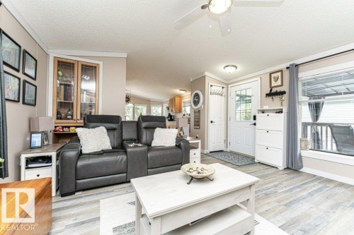 Open concept living area featuring wood-finish flooring, a ceiling fan with integrated lighting, and a white paneled entry door - 233 Oak Wood Drive, Edmonton, AB 