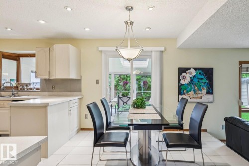 Kitchen and dining area featuring white cabinetry, light-toned countertops, and a white tiled floor - 15804 80 Street, Edmonton, AB 
