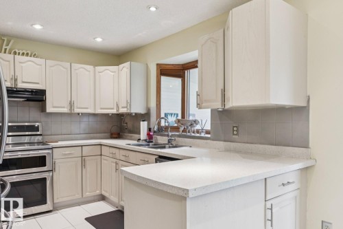 Kitchen featuring light-toned cabinetry, light-colored countertops, and stainless steel double ovens - 15804 80 Street, Edmonton, AB 