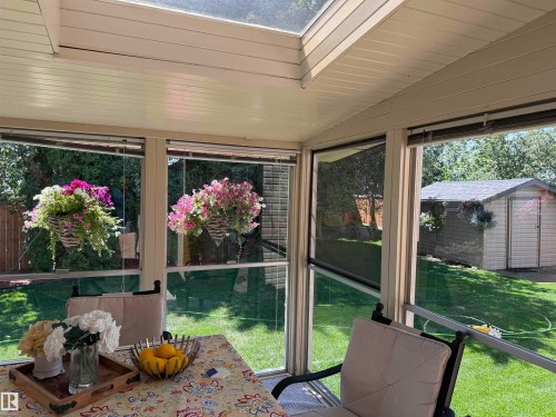 Sunroom featuring a skylight, expansive windows, a solid panel ceiling, and a view of the backyard with a utility shed - 15804 80 Street, Edmonton, AB 