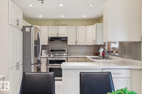 Kitchen featuring white cabinetry, stainless steel appliances, recessed lighting, a tile backsplash, and light-colored countertops - 15804 80 Street, Edmonton, AB 