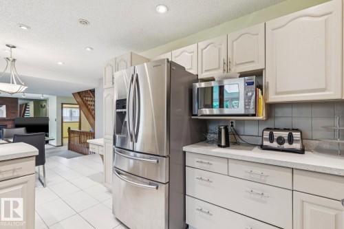 Kitchen featuring white cabinetry, light-toned countertops, and a white tile floor - 15804 80 Street, Edmonton, AB 