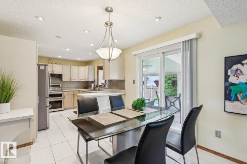 Kitchen and dining area featuring white tile flooring, recessed lighting, and a contemporary chandelier - 15804 80 Street, Edmonton, AB 