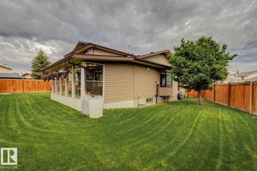 Expansive backyard featuring a manicured lawn, a mature tree, and a full privacy fence - 15804 80 Street, Edmonton, AB 