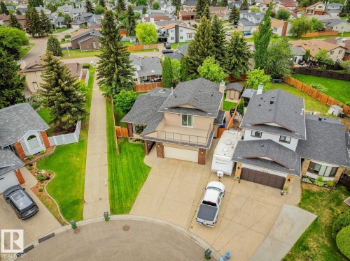 Residential property featuring a two-story home with a tan exterior, dark shingle roof, and an upper-level balcony - 15804 80 Street, Edmonton, AB 