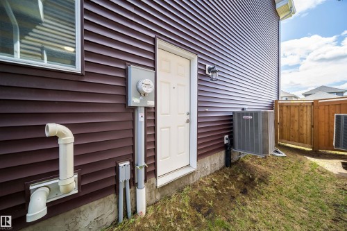 Dark brown horizontal siding exterior featuring a white entry door, an exterior light fixture, and a visible electrical meter - 16123 31 Avenue, Edmonton, AB 