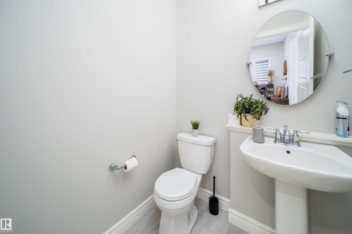 Pedestal sink with chrome faucet, circular wall mirror, and light gray wall paint - 16123 31 Avenue, Edmonton, AB 