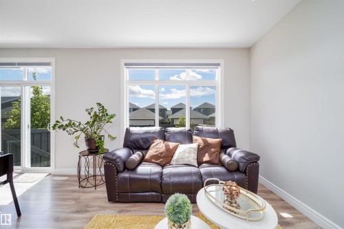 Bright interior space featuring a large window, white walls, wood-finish flooring, and white trim - 16123 31 Avenue, Edmonton, AB 