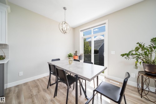 Dining area featuring wood-finish flooring and a contemporary spherical chandelier - 16123 31 Avenue, Edmonton, AB 