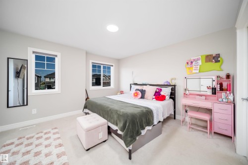 Spacious bedroom featuring light neutral wall tones, two paneled windows with white trim, and a ceiling-mounted circular light fixture - 16123 31 Avenue, Edmonton, AB 