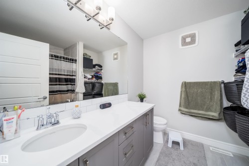 Contemporary bathroom vanity featuring a light-colored countertop with an integrated sink, polished chrome faucet, and gray cabinetry with brushed nickel hardware - 16123 31 Avenue, Edmonton, AB 