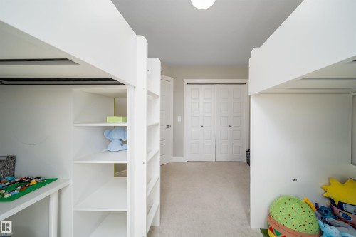 Carpeted room featuring two white built-in loft beds with integrated shelving and desks - 16123 31 Avenue, Edmonton, AB 