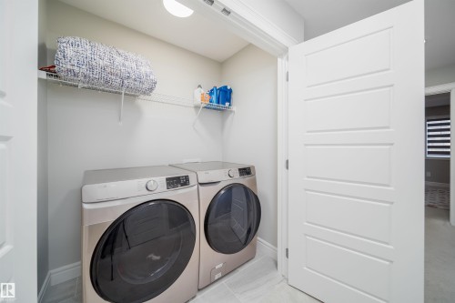 Dedicated laundry area with light gray walls, light-toned flooring, and built-in wire shelving - 16123 31 Avenue, Edmonton, AB 