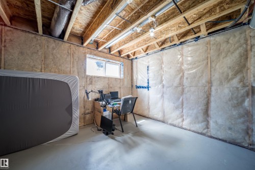 Unfinished basement space featuring exposed wood joists, insulated walls, concrete flooring, and an egress window - 16123 31 Avenue, Edmonton, AB 