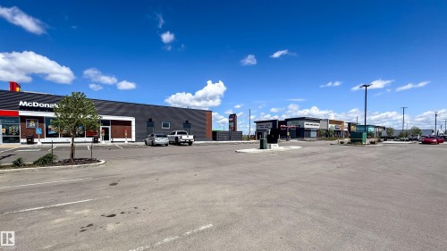 Expansive commercial parking lot with a modern McDonald's restaurant featuring dark brick and red accents - 16123 31 Avenue, Edmonton, AB 