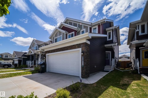 Contemporary exterior featuring dark horizontal siding, stone veneer accents, and a white garage door - 16123 31 Avenue, Edmonton, AB 