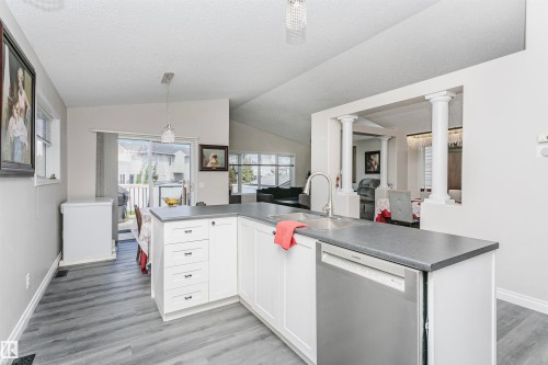 Kitchen island with a stainless steel undermount sink, a chrome gooseneck faucet, and integrated stainless steel dishwasher - 4228 162 Avenue, Edmonton, AB 
