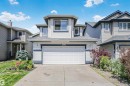 Two-story residence featuring light-colored siding with dark trim accents, an attached two-car garage, concrete driveway, and mature landscaping - 4228 162 Avenue, Edmonton, AB 