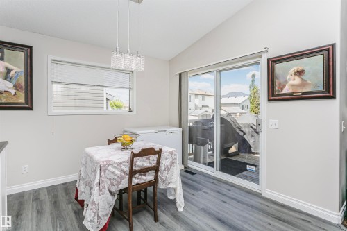 Dining area featuring wood-finish flooring, a vaulted ceiling, a rectangular window with blinds, and a sliding glass door providing access to an exterior deck - 4228 162 Avenue, Edmonton, AB 