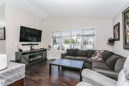 Spacious living area featuring vaulted ceilings, wood-finish flooring, and a wide window providing natural light - 4228 162 Avenue, Edmonton, AB 