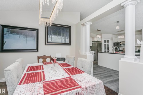Dining area featuring a linear crystal chandelier, vaulted ceiling, and two decorative wall art pieces - 4228 162 Avenue, Edmonton, AB 