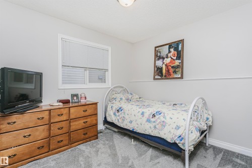 Room featuring light gray wall paint, textured ceiling, a window with horizontal blinds, and gray patterned carpeting - 4228 162 Avenue, Edmonton, AB 