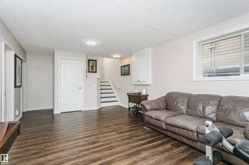 Spacious room featuring wood-finish flooring, light-toned walls, and abundant natural light from a prominent window - 4228 162 Avenue, Edmonton, AB 