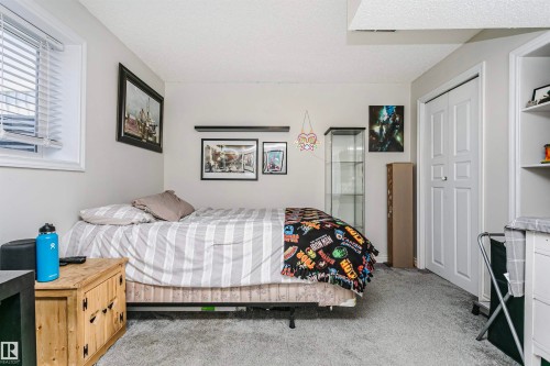 Carpeted room with a double-width closet, built-in shelving, a window with horizontal blinds, and a built-in shelf - 4228 162 Avenue, Edmonton, AB 