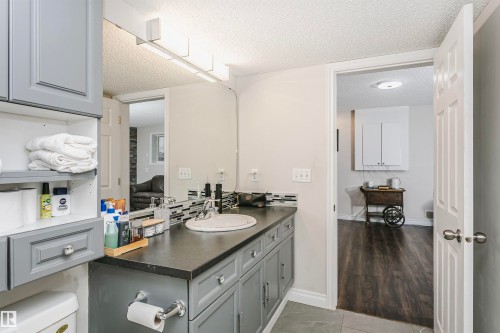 Bathroom vanity with grey cabinetry, a white oval sink, and a dark countertop - 4228 162 Avenue, Edmonton, AB 